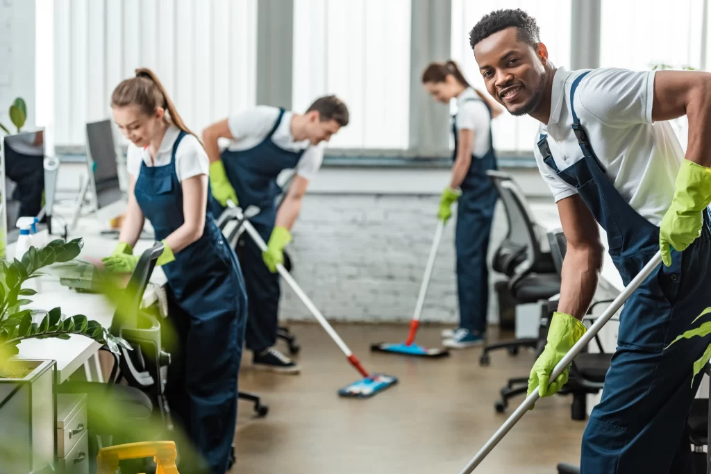 A Group of workers smiling while cleaning an office